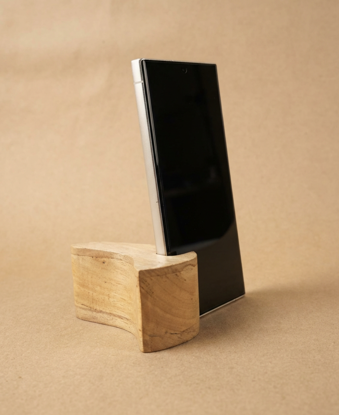 A minimalist wooden phone stand designed for stable, hands-free viewing with a natural, modern aesthetic.