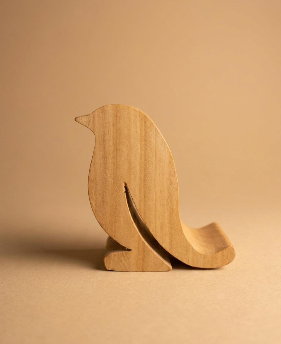 A handcrafted wooden bird-shaped phone stand that blends functionality with minimalist decor.